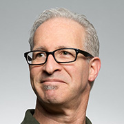 Man with glasses in front of gray wall