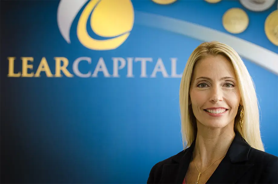 Woman smiling in front of Lear Capital logo on wall
